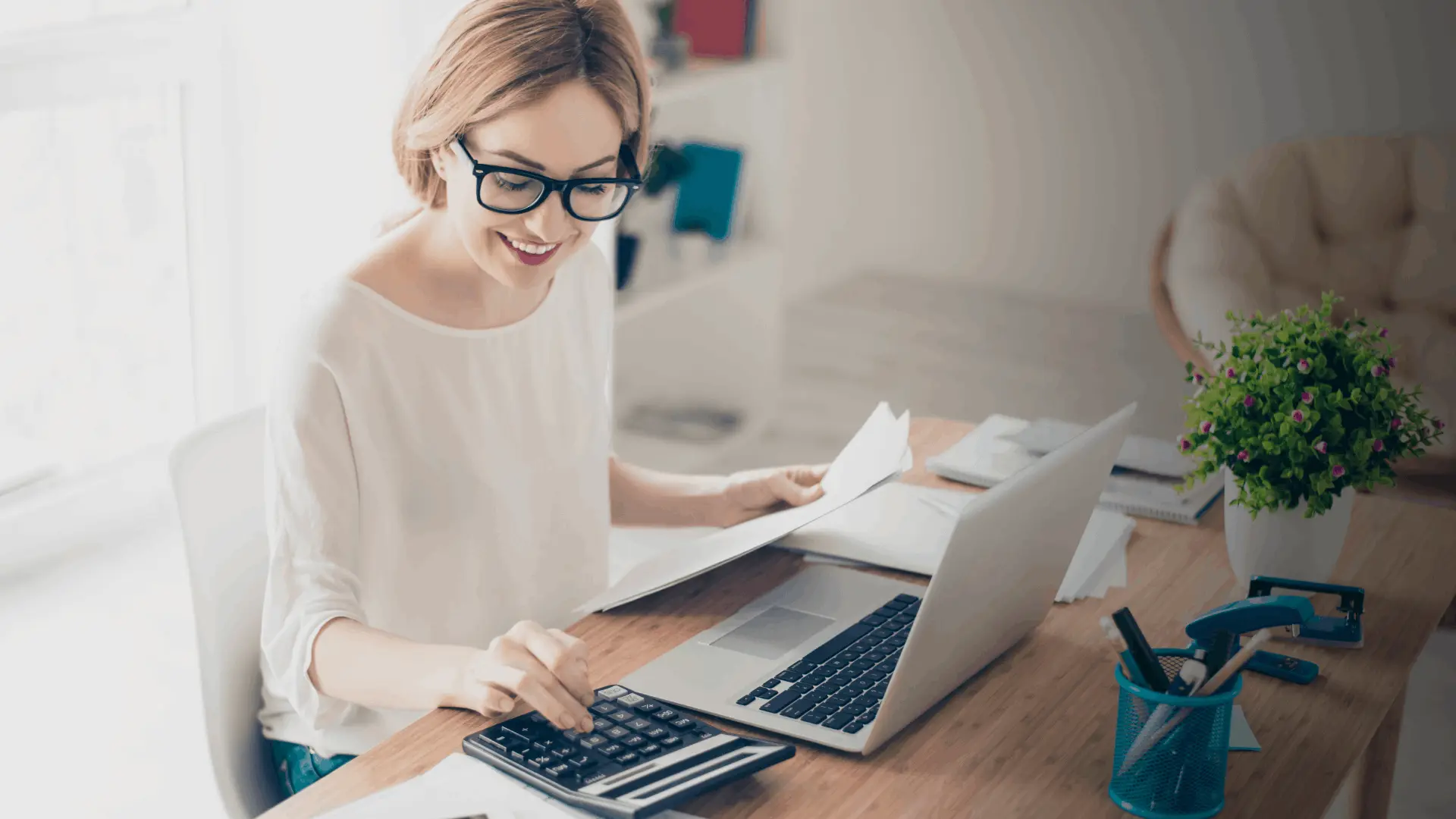 A bookkeeper working through paperwork at a bright desk